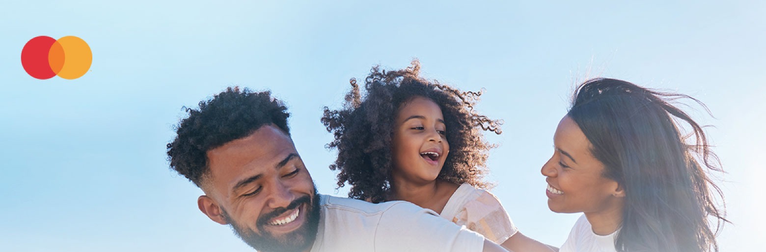 Man, child and woman smiling in front of a blue sky