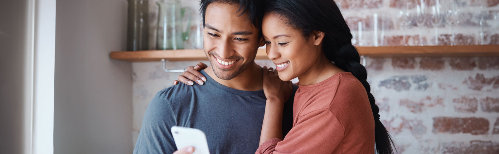 Man and woman in kitchen looking at a cell phone together.