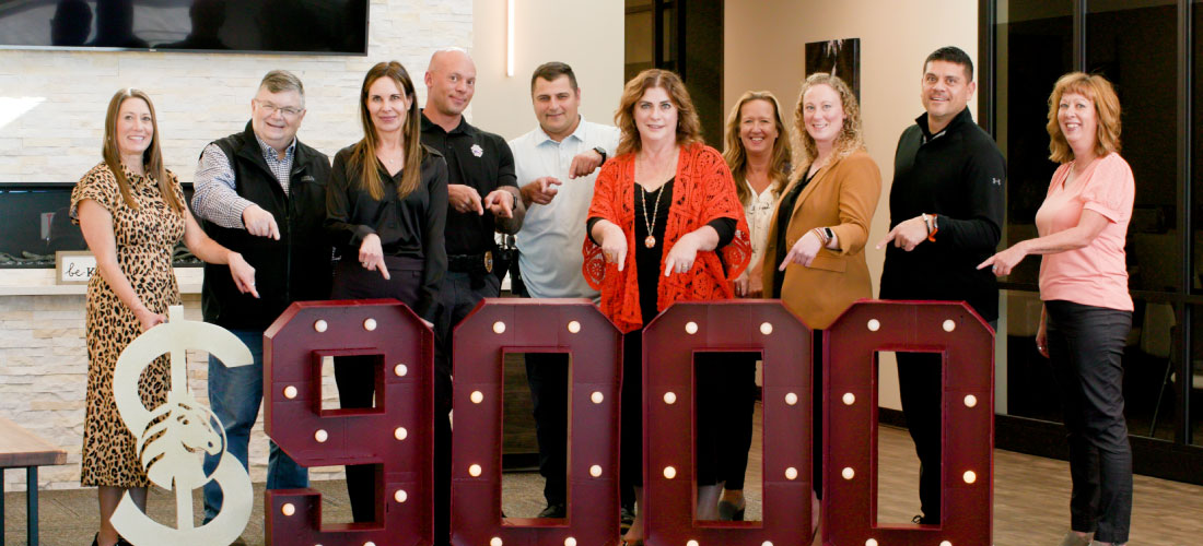 Members of Family Tree Nurturing Center, Billings Police, and Yellowstone Boys and Girls Ranch with First Federal employees pointing at $9000 marquee numbers.