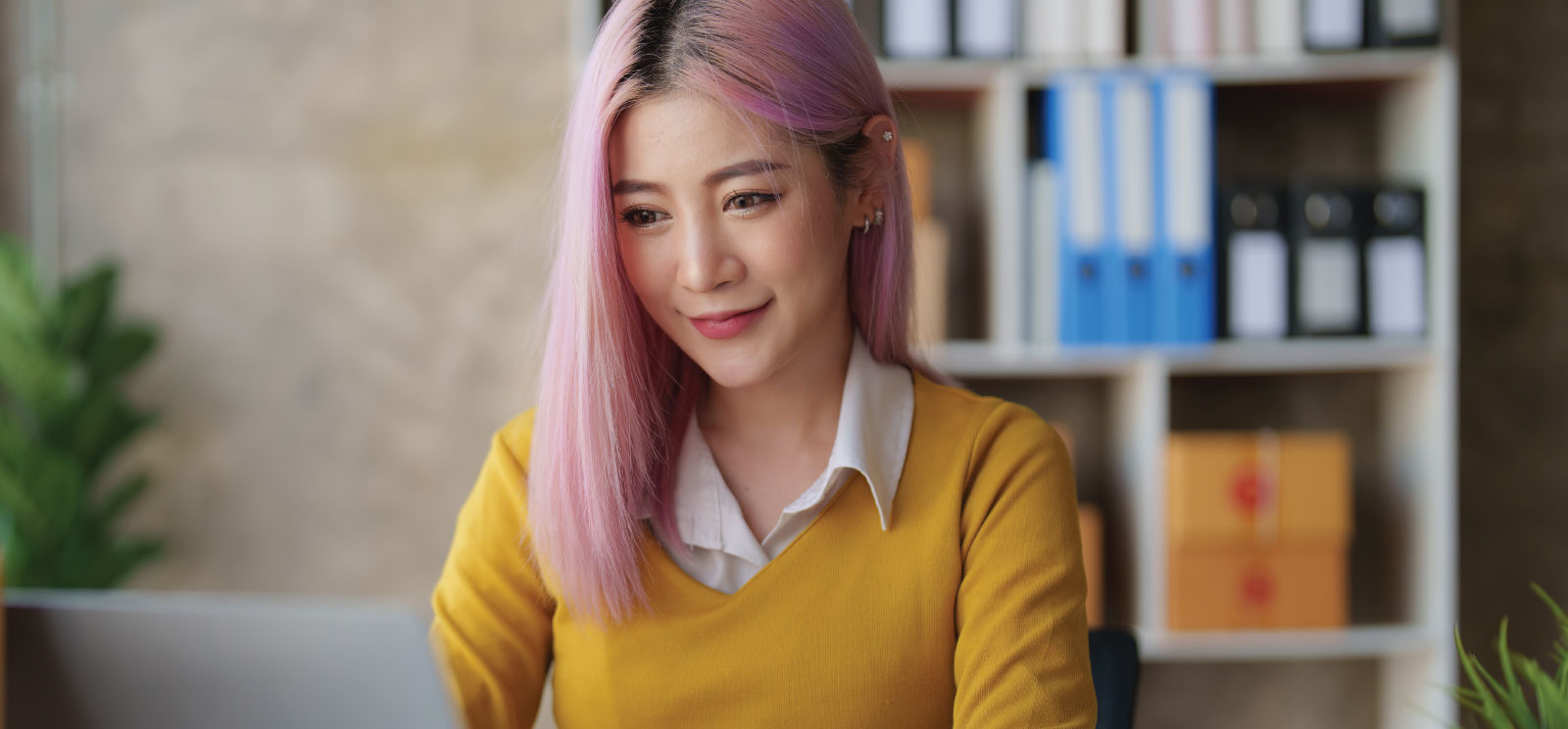 Woman with pink hair working on laptop