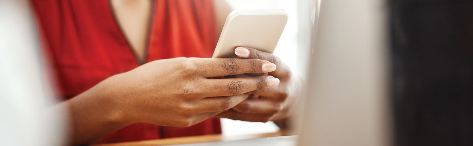 Woman in orange holding a cell phone.