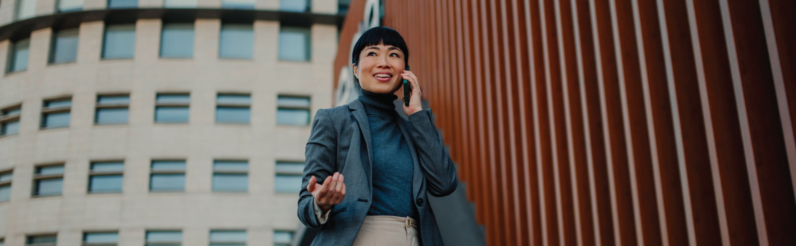 Businesswoman on a phone in front of office buildings.
