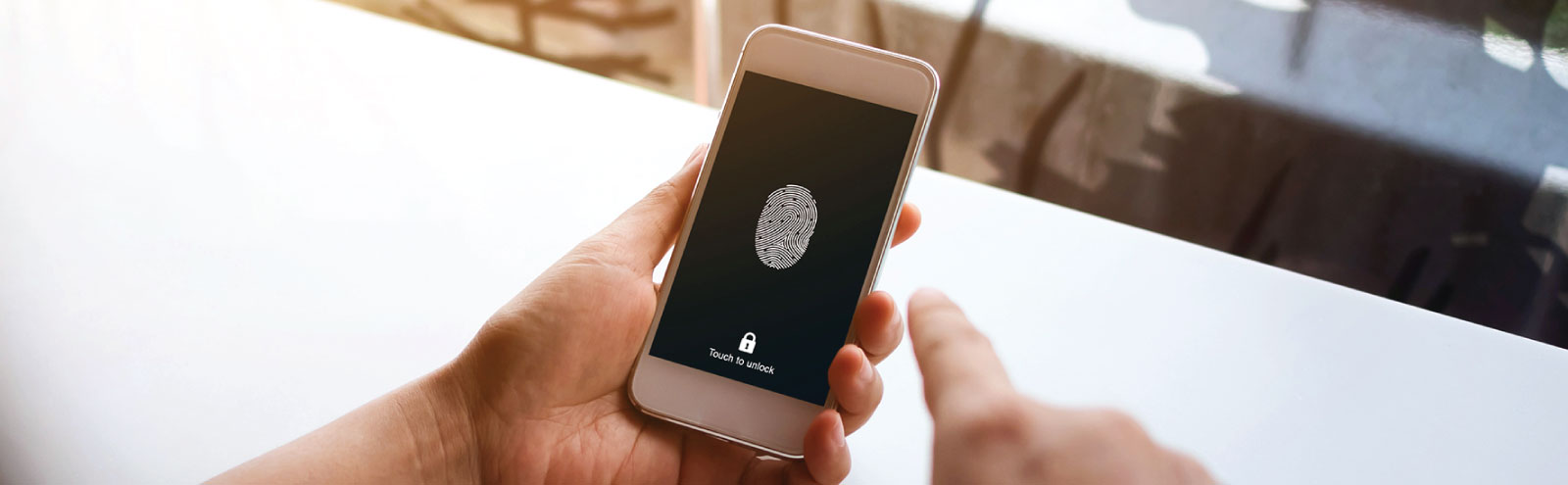 Hands holding a mobile phone with fingerprint security.