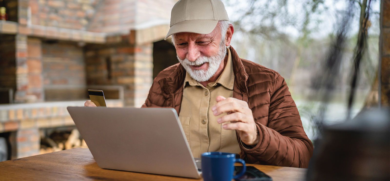 Older man using laptop outside.