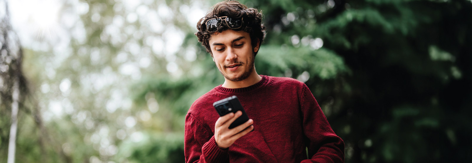 Man in park looking at mobile phone.