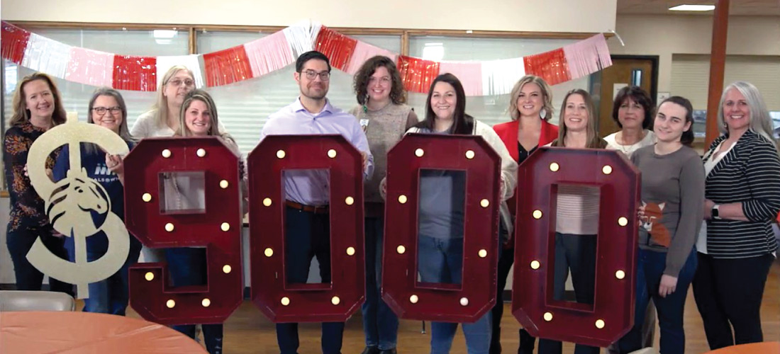 Group of people holding $9,000 marquee numbers.