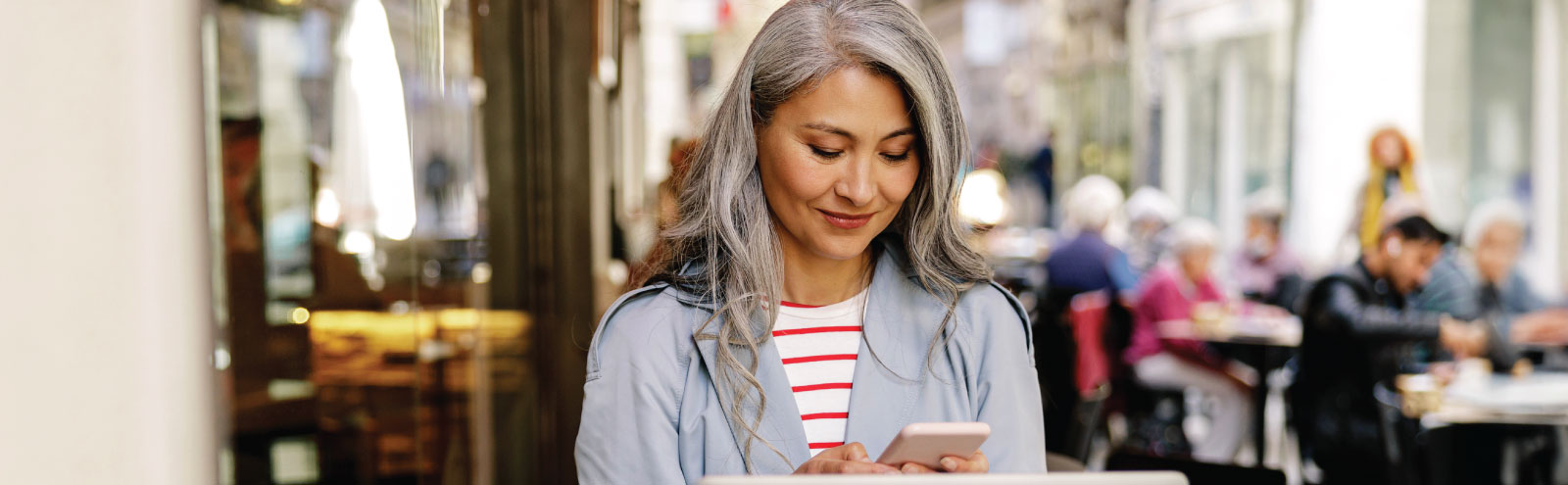 Woman looking at her phone at an outdoor cafe.