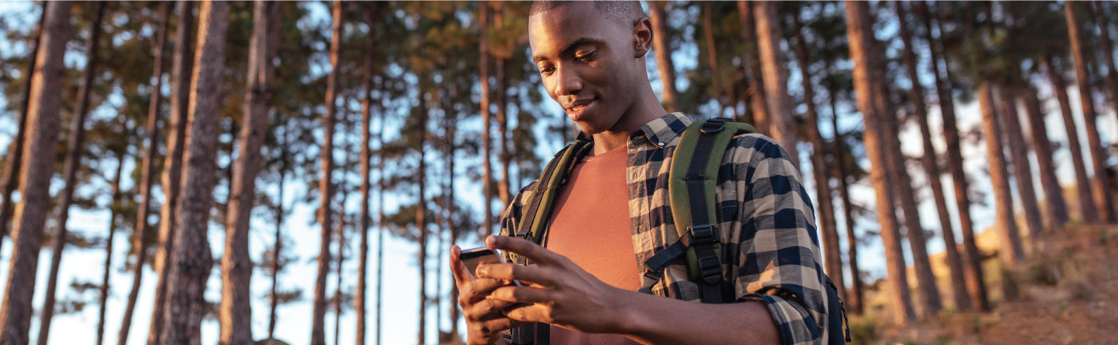 Man looking at phone while hiking in forest