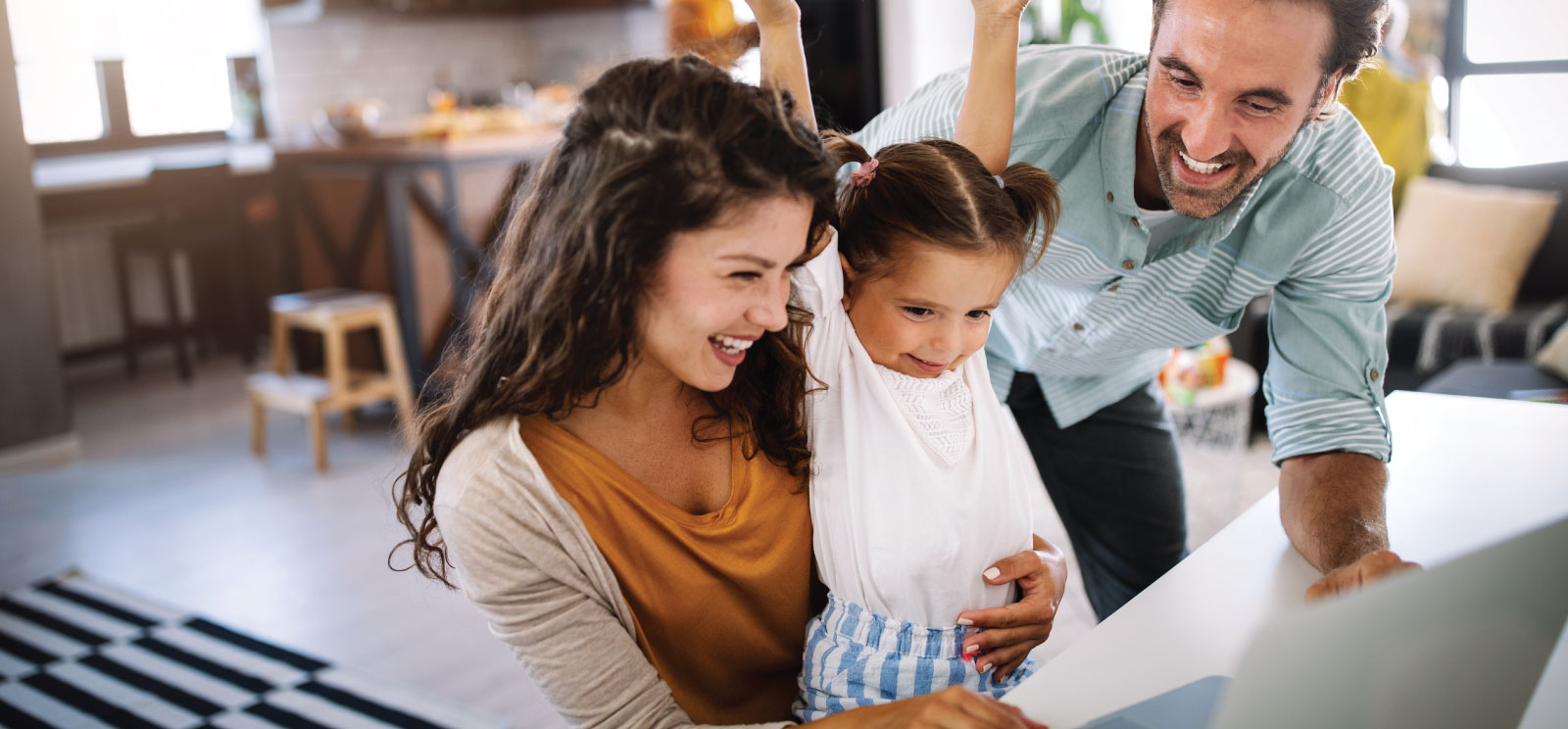 Child cheers with her mom and dad while looking at a laptop