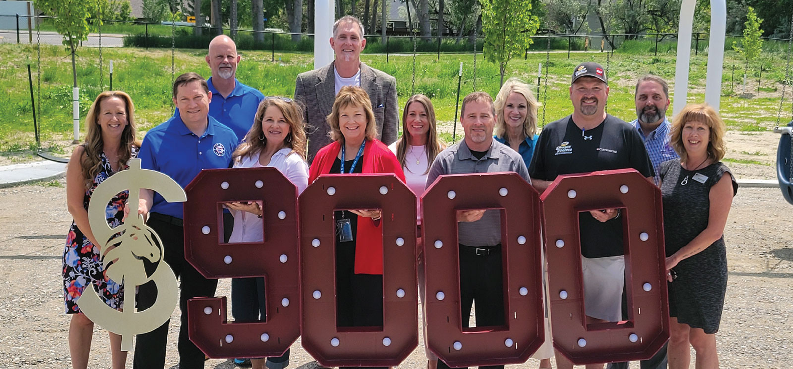 Group of First Federal employees with Landon's Legacy holding $9,000 marquee numbers.