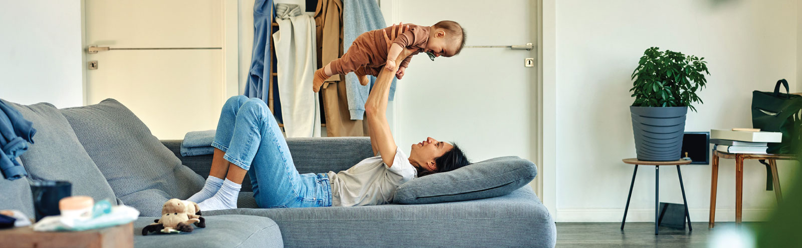 Woman lifting her happy baby up on her couch in the living room.